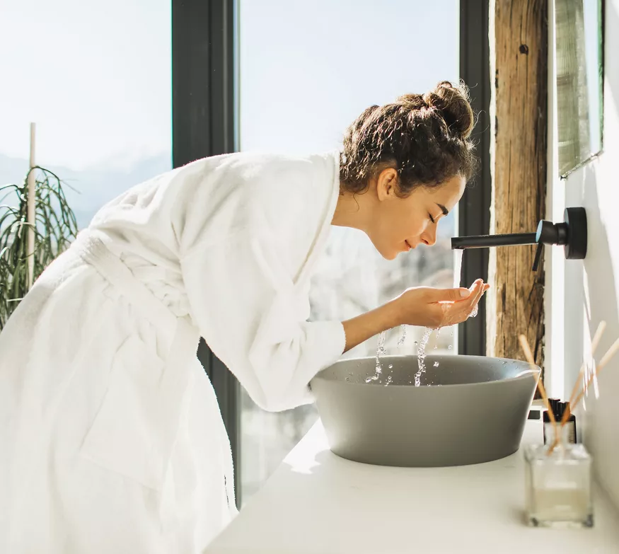 Kvinne vasker ansiktet på badet