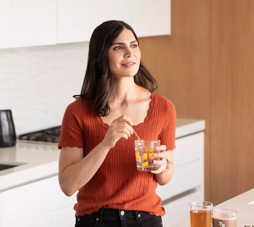 Kvinne drikker Aloe Max på kjøkkenet